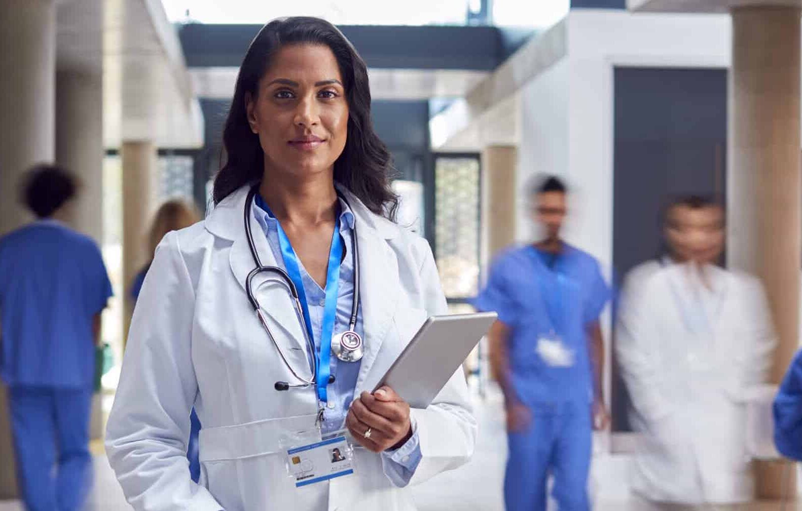 A doctor looks into the camera holding a tablet